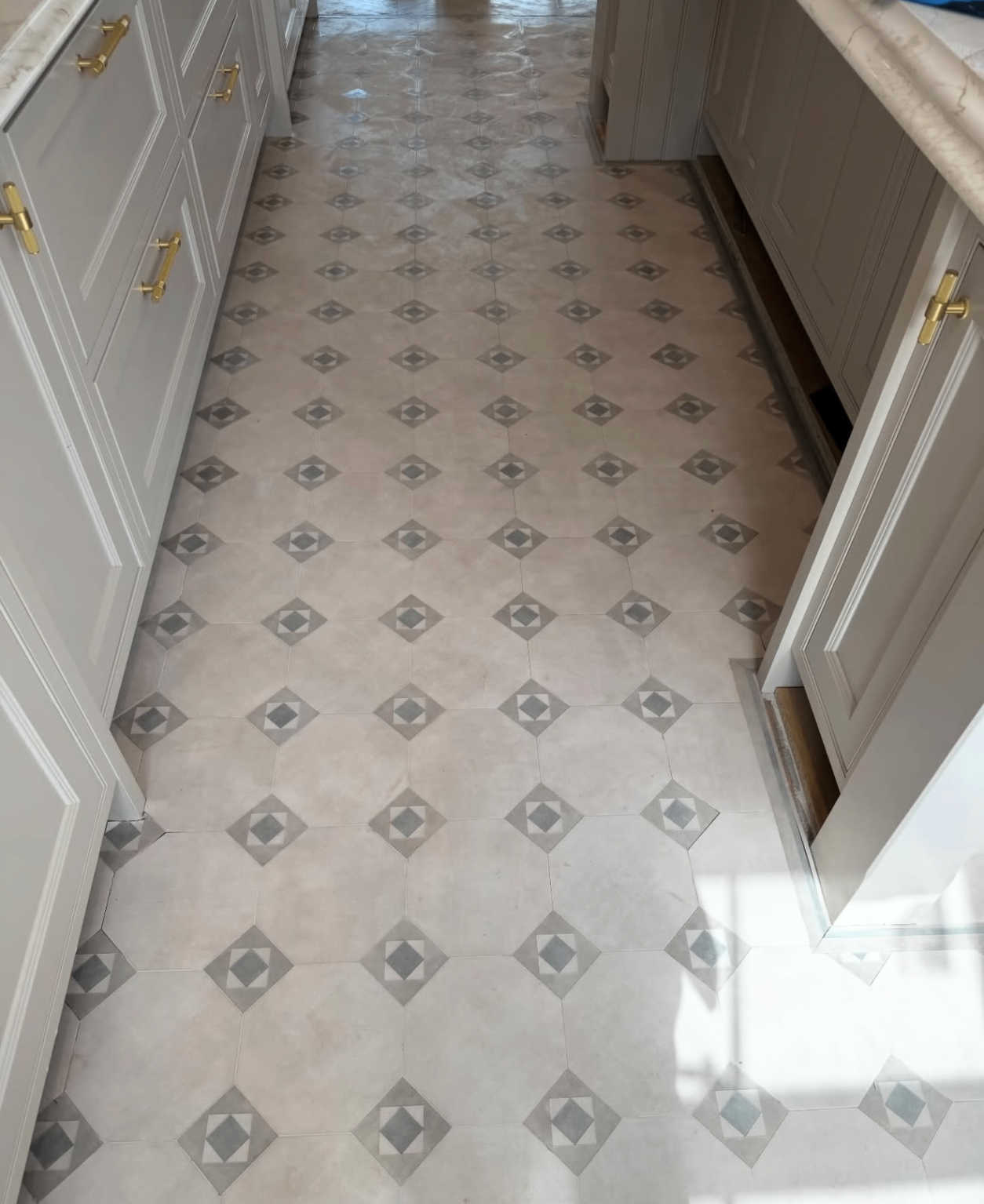 Long galley kitchen with geometric stone-effect floor tiles
